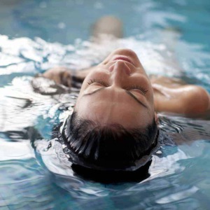 Frau liegend im Pool und genießt ihren Wellnessurlaub