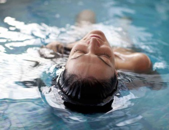 Frau liegend im Pool und genießt ihren Wellnessurlaub