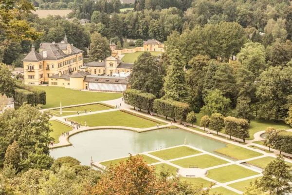 Gelbes Gebäude mit einem Garten im Vordergrund und Bäumen im Hintergrund