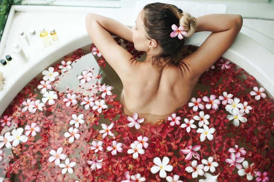 Frau in einem mit Blüten gefülltem Bad